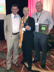 Three people facing the camera to take a photo with an award